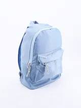Mochila de diseño clásico en color celeste, confeccionada en material sintético con acabado brillante. Cuenta con un compartimento principal amplio con cierre, un bolsillo frontal externo con cierre y tiradores de cordón trenzado en blanco y negro.