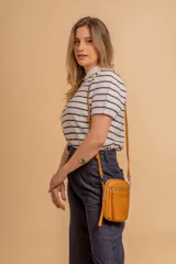 Bandolera compacta color rosado, con correa regulable y desmontable. Tiene apertura superior, bolsillo frontal con cierre y detalle de borla, y bolsillo trasero sin cierre. El interior está forrado en tela y cuenta con un bolsillo adicional.