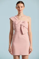 Vestido corto color rosado de Natalia Antolin, modelo Rouge. Diseño de un solo hombro con detalle de lazo drapeado estructurado en el pecho, corte entallado y silueta recta.