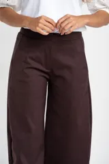 Pantalon de corte baggy y tiro medio, color marrón oscuro, con diseño de pierna ancha y bolsillos laterales.