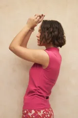 Top negro sin mangas con cuello alto y fruncido en los laterales. Es elastizado y cuenta con un botón a tono en la espalda.