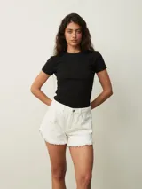 Short de jean color blanco roto (off white) de tiro alto, con roturas y terminación deshilachada en el ruedo.