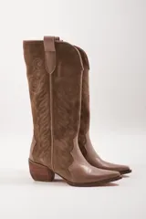 Botas texanas de cuero color beige con detalles bordados en negro y caña alta.