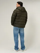 Campera puffer Tommy Hilfiger de color verde militar, con diseño acolchado horizontal, capucha integrada con interior azul y cierre frontal de cremallera. Cuenta con bolsillos laterales con cierre y el logo bordado en el pecho.