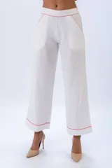 Pantalón blanco de lino y algodón, de corte ancho y cintura elastizada, con bolsillos laterales y terminaciones con sesgo a contratono color coral.