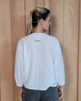 Camisa de manga larga con diseño de rayas verticales y bordados sutiles. Presenta cuello redondo, cierre frontal con botones y mangas abullonadas con volados en los hombros.