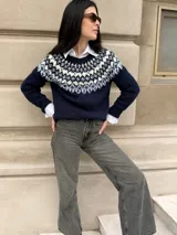 Sweater tejido de punto con diseño jacquard en la parte superior, cuello redondo y mangas largas. Presenta una combinación de colores azul marino, blanco y celeste.