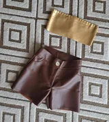 Short de cuero color marrón con botón blanco.