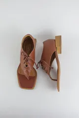 Sandalias de cuero color beige con diseño de ojota acordonada en el empeine, puntera cuadrada y taco bajo cuadrado.