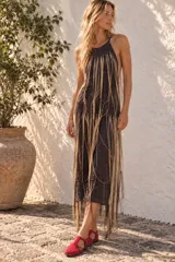 Vestido midi de crochet con hilos de lúrex en tono oscuro, cuello halter y diseño sin mangas, decorado con flecos largos colgantes.