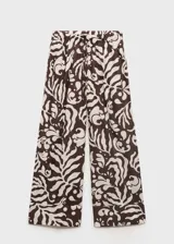 Pantalon de corte recto y tiro medio, con cintura elástica y cordón ajustable. Presenta un estampado abstracto de hojas en tonos marrones y crema, y cuenta con dos bolsillos laterales.