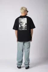 Remera de corte oversize confeccionada en algodón premium de alto gramaje. Presenta un diseño minimalista con un pequeño logo bordado en el centro del pecho y un parche estampado en la espalda. Posee cuello redondo y mangas cortas con caída relajada.