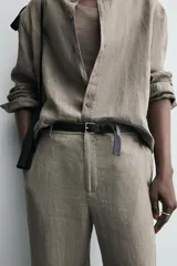 Camisa de manga larga color verde oliva, confeccionada en lino lavado con efecto ligeramente arrugado. Presenta cuello italiano y cierre frontal de botones.