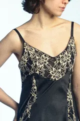 Musculosa de satén negro con inserciones de encaje beige con motivo floral en el escote y los laterales, tirantes finos y silueta acampanada.