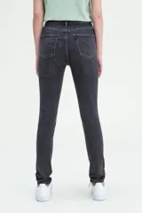 Pantalón de jean negro gastado, tiro alto, corte ajustado en cadera y muslos, y pierna skinny.