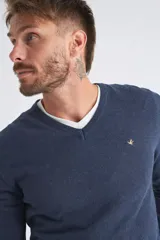 Sweater de tejido de punto color beige, con escote en V, mangas largas y puños y dobladillo acanalados. Presenta un pequeño logo bordado en el pecho.