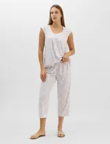 Pijama compuesto por remera sin mangas con escote redondo, botones frontales y detalle de puntilla, acompañado de un pantalón capri con cintura elástica. Presenta un estampado floral en tonos rosados sobre base gris.