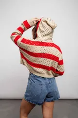 Buzo de tejido de punto calado color beige con rayas horizontales rojas y capucha.