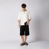 Bermuda sastrera gris de corte baggy, con pinzas al frente y diseño holgado que se extiende por debajo de la rodilla.