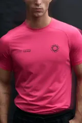 Remera deportiva de compresión color fucsia, con cuello redondo y mangas raglán. Presenta costuras planas antifricción y estampado gráfico en el pecho con la leyenda 365 Training Team.