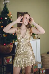 Vestido corto negro con estampado de plumas doradas, escote en V, breteles finos cruzados en la espalda, cut-outs laterales y volado en el ruedo.