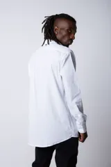 Camisa de manga larga en tela popelín color blanco, con cuello mao y cierre frontal de botones.