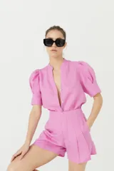 Short de lino color rosa con cintura alta, pinzas delanteras, bolsillos laterales y cierre frontal con gancho metálico.