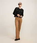 Pantalón de mujer modelo flare, confeccionado en punto roma color marrón, con cintura alta, bolsillos delanteros de solapa, bolsillos traseros embutidos y cierre delantero con cremallera.