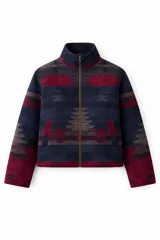 Campera de lana italiana con diseño de motivos tribales en tonos oscuros, rojos y beige. Presenta cierre frontal, bolsillos laterales y detalle de flecos largos de gamuza en las mangas.