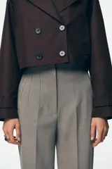 Pantalón blanco de vestir, de tiro alto y corte recto. Presenta bolsillos delanteros de vivo y cierre frontal con cremallera, botón interior y gancho metálico.