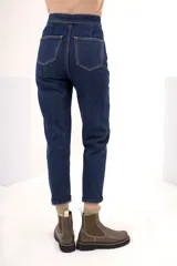 Pantalón jean azul oscuro de tiro alto con pierna recta, pretina con botones metálicos y cierre frontal con botón y cremallera.