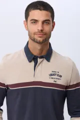 Remera polo de manga larga con diseño de bloques de color en tonos beige, bordó y azul marino. Presenta cuello clásico, cierre frontal con botones y estampa bordada en el pecho.