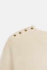 Jersey negro de punto de manga corta y cuello redondo, con detalle de botones dorados en el hombro.
