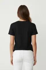 Remera blanca de manga corta y cuello redondo, con un estampado circular de lentejuelas doradas y plateadas en el frente.