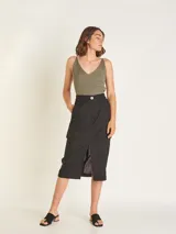 Falda midi color beige, de tiro alto con elástico en la cintura trasera, cierre y botón delantero. Tiene bolsillos delanteros y bolsillos cargo a los costados, con tajo en el delantero.