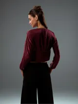 Top corto color bordó, con escote en V, mangas largas abullonadas con puños elásticos y fruncido en la parte delantera.
