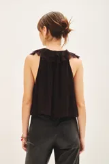 Top negro sin mangas con escote profundo, detalle de volados frontales y lazos para anudar en el cuello.