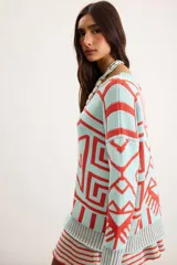 Buzo oversize de punto color marfil con diseño geométrico jacquard en tonos rosado, amarillo, celeste y marrón. Cuenta con cuello redondo y mangas largas.