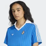 Vestido Adidas del Real Madrid, inspirado en las camisetas de fútbol de los años ochenta. Diseño azul con rayas verticales blancas, cuello polo blanco con detalles en dorado y escudo del Real Madrid bordado.