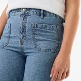 Pantalón jean de tiro alto y pierna ancha, de color azul medio con lavado suave. Presenta bolsillos de parche delanteros, costuras decorativas y un delicado bordado floral blanco en el ruedo.
