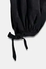 Pantalón negro de tiro alto con cintura elástica y bajo ajustado con lazada.