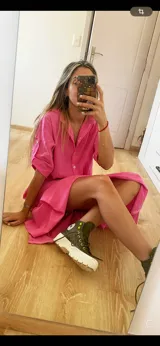 Vestido camisero midi color verde oliva, con cuello clásico, mangas cortas con trabillas y botones dorados, y cierre frontal con botones dorados.