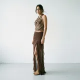 Falda larga de tul color marrón, con diseño de volados en cascada y tajo lateral pronunciado. Presenta un fruncido central en la parte delantera.