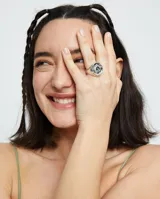 Anillo tipo sello plateado con forma de ojo y cristal facetado verde.