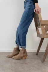 Bota corta de cuero gamuzado color negro, con punta fina y diseño bordado estilo western. Tiene un pequeño tirador en la parte trasera y un taco cónico de altura media.