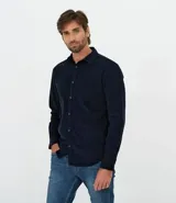 Camisa de manga larga confeccionada en terciopelo de algodón, con cuello clásico, cierre frontal de botones y bolsillo aplicado en el pecho.