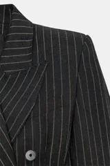 Blazer vestido de Zara con diseño de raya diplomática, cuello solapa con muesca, hombreras marcadas y cierre frontal cruzado con botones. Presenta una cintura entallada con volumen y falso bolsillo de vivo en el pecho.