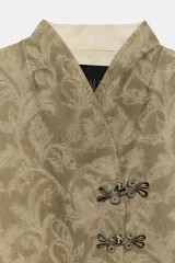 Blazer de corte recto confeccionado en tejido jacquard con diseño floral en tonos tostados. Presenta cuello mao, manga larga y cierre frontal mediante alamares decorativos. Incluye bolsillos de vivo en el delantero.