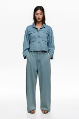 Pantalón de jean ancho de corte wide leg en color celeste, confeccionado en algodón, con tiro bajo, bolsillos laterales y cierre frontal con botón y cremallera.