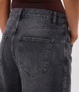 Pantalón de jean color azul oscuro, modelo baggy balloon de tiro medio, con bolsillos funcionales, trabillas en la cintura y recortes laterales que aportan una silueta redondeada.
